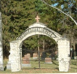 Picture of the stone and iron gate to the cemetery. There is an arch over the gate.
