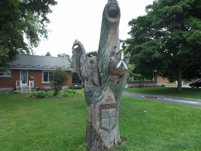 Picture of a tree sculpture showing crest of Arthur, heron, own, coyote